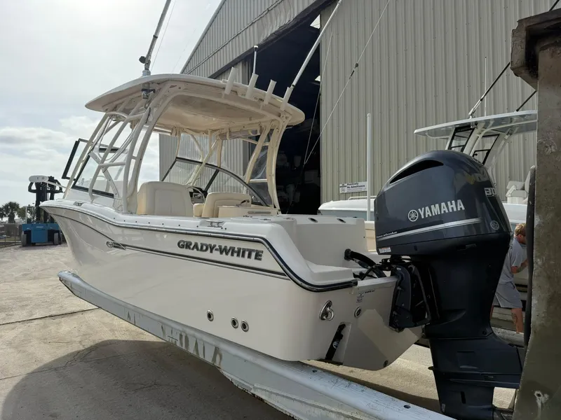 Slide: The Image of 2015 Grady-White Freedom 255 boat with Yamaha engine, docked near a large warehouse. - 3