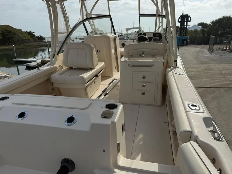Slide: The Image of 2015 Grady-White Freedom 255 boat interior with seating and console, docked by the water. - 5