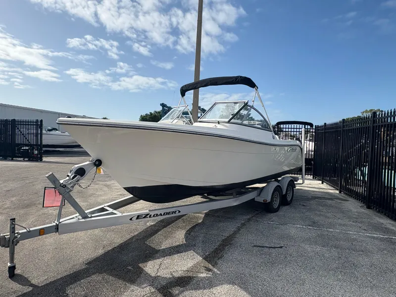 Slide: The Image of 2020 Cobia 220 Dual Console boat on trailer, parked outdoors under a clear sky. - 2