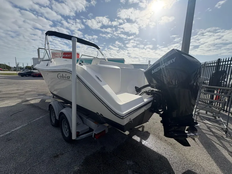 Slide: The Image of 2020 Cobia 220 Dual Console boat on trailer with Mercury outboard motor, parked outdoors. - 4