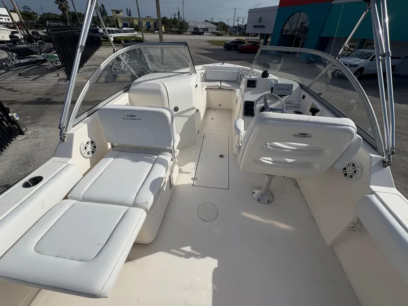 Slide: The Image of 2020 Cobia 220 Dual Console boat with white seating and spacious deck layout. - 5