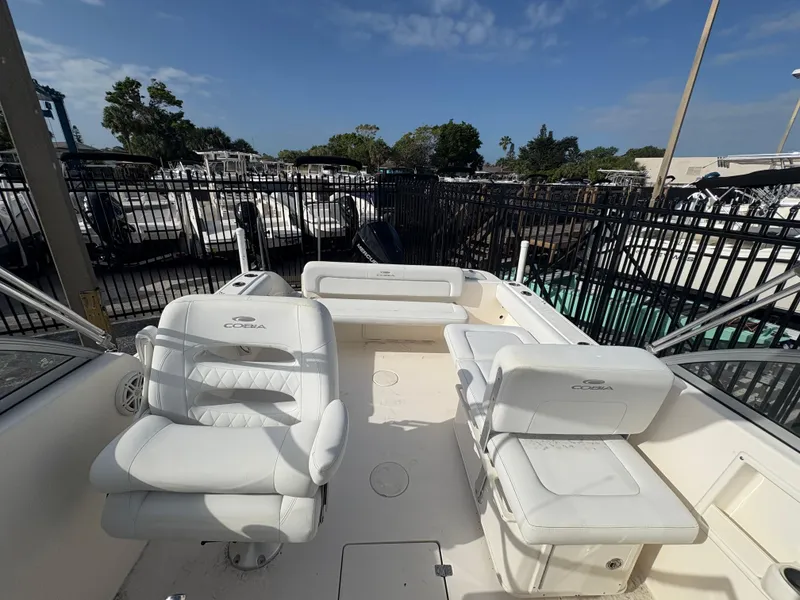 Slide: The Image of 2020 Cobia 220 Dual Console boat interior with white seating, docked under clear skies. - 8