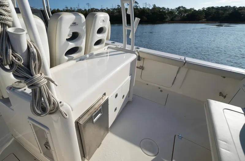 Slide: The Image of 2022 Cobia 350 Center Console boat interior with seating and storage, near a serene waterway. - 12