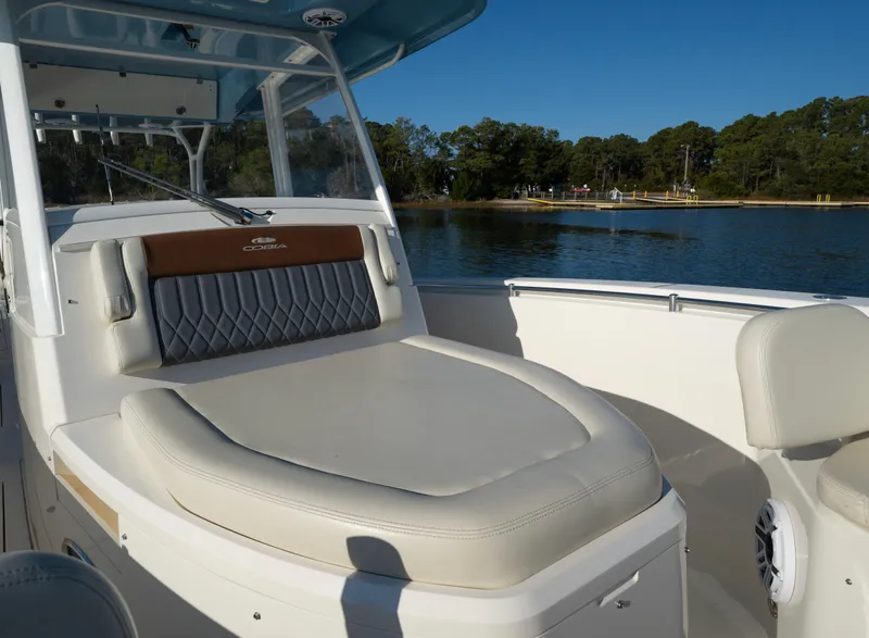 Slide: The Image of 2022 Cobia 350 Center Console boat with cushioned seating, on a calm lake. - 7