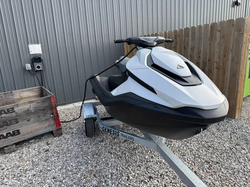 Slide: The Image of 2024 Taiga Orca jet ski on Genesis trailer, parked on gravel near wooden fence. - 10
