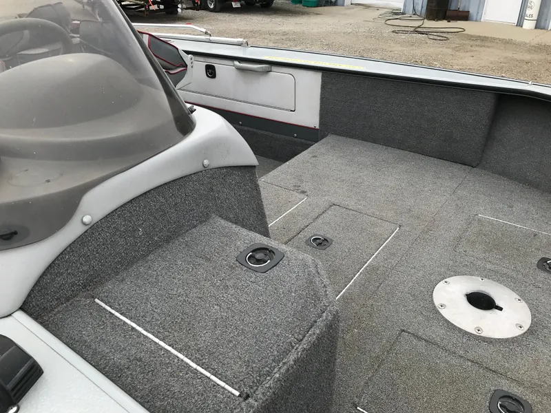 Slide: The Image of 1998 Lund 1775 Pro-V SE boat interior with gray carpet and storage compartments. - 16