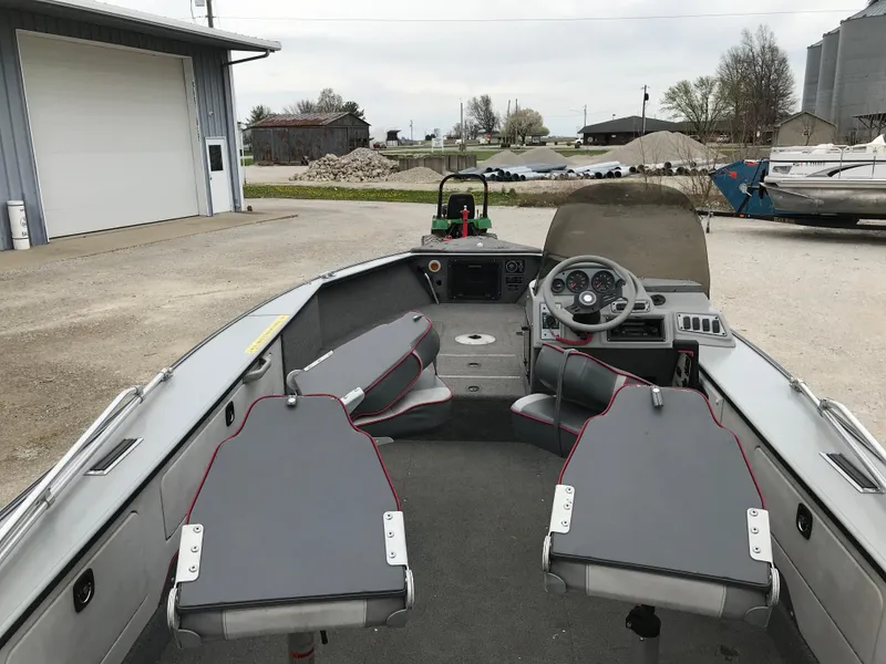 Slide: The Image of 1998 Lund 1775 Pro-V SE boat interior with steering wheel and seating, parked outdoors. - 22