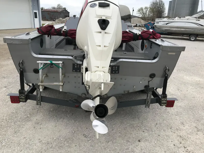 Slide: The Image of 1998 Lund 1775 Pro-V SE boat with outboard motor on trailer, parked outdoors. - 4