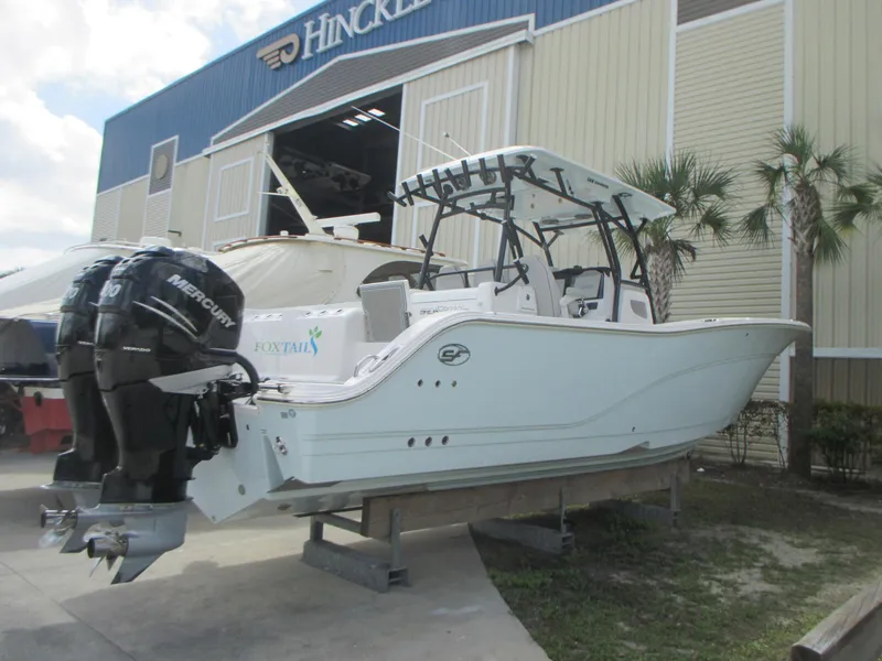 Slide: The Image of 2023 Sea Fox 328 Commander boat with dual Mercury engines, displayed outside a Hinckley building. - 2