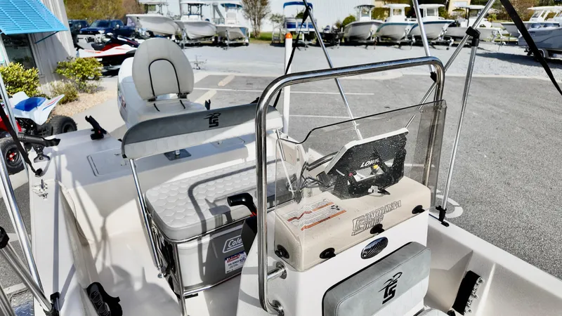 Slide: The Image of 2024 Carolina Skiff e18 JVX boat interior with console and seating, displayed outdoors. - 12