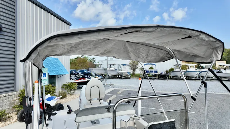 Slide: The Image of 2024 Carolina Skiff e18 JVX boat with canopy, parked near a marina. - 9
