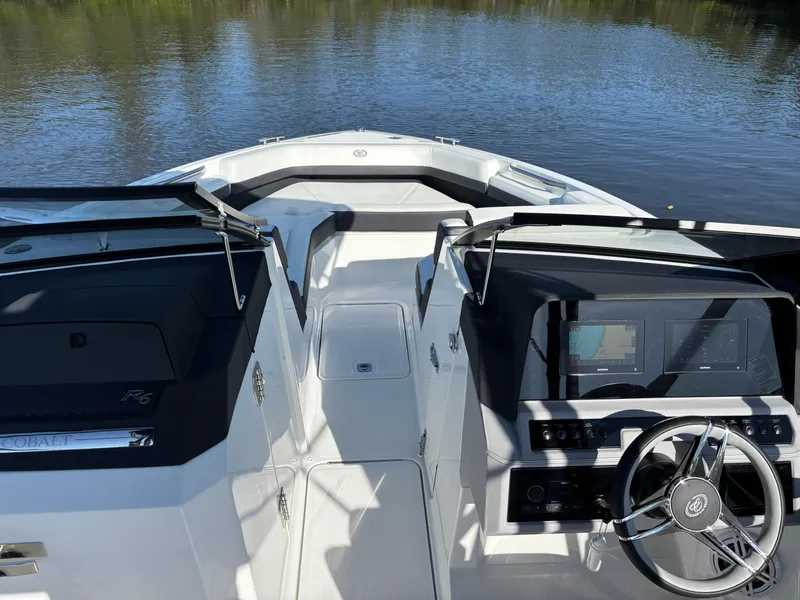 Slide: The Image of 2025 Cobalt R6 Outboard boat interior with sleek dashboard and steering wheel on calm water. - 6