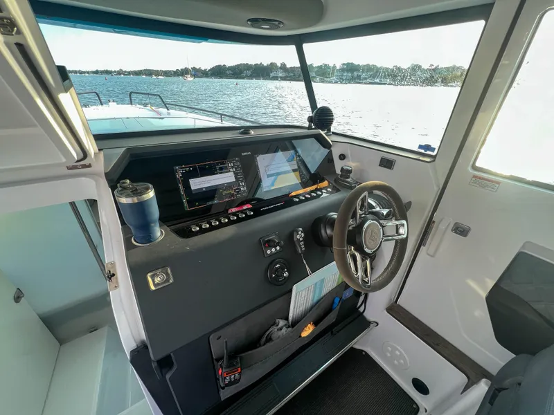 Slide: The Image of 2020 Axopar 37 XC boat cockpit with steering wheel and navigation screens, overlooking water. - 10