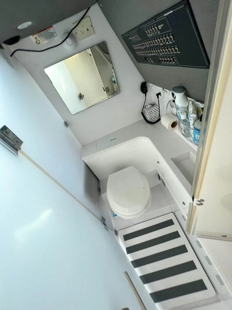Slide: The Image of 2020 Axopar 37 XC boat bathroom with toilet, mirror, and control panel. - 16