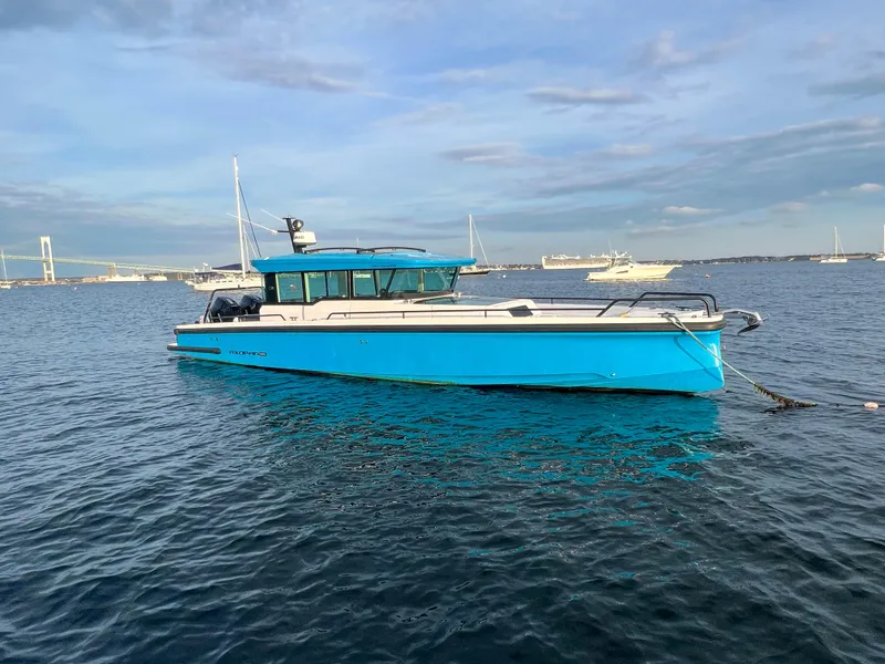 Slide: The Image of 2020 Axopar 37 XC boat in blue, anchored on calm water with a scenic background. - 3