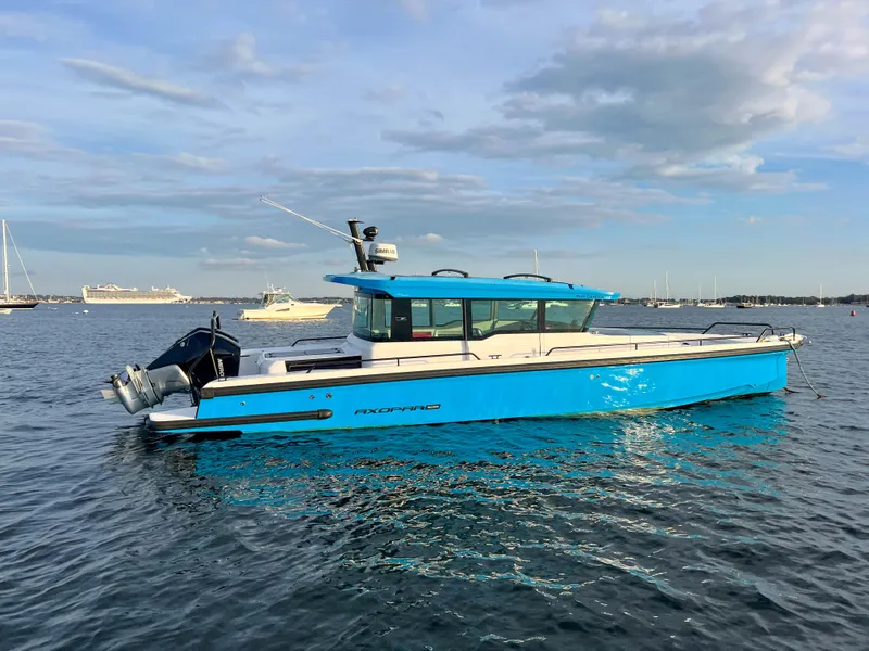 Slide: The Image of 2020 Axopar 37 XC boat on calm water, blue and white design, side view. - 4