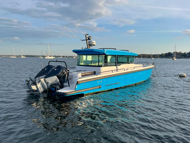 Slide: The Image of 2020 Axopar 37 XC boat in blue, anchored on calm water under a clear sky. - 5