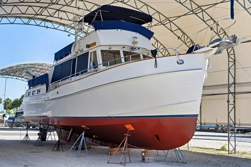 The Image of 1994 Grand Banks 49 Motoryacht under a canopy, showcasing its classic design and red hull. - 0