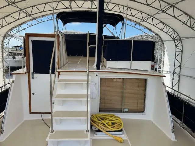 Slide: The Image of 1994 Grand Banks 49 Motoryacht under canopy, featuring stairs and coiled yellow hose on deck. - 3