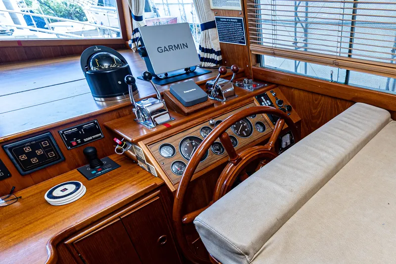 Slide: The Image of 1994 Grand Banks 49 Motoryacht helm with Garmin navigation, wooden steering wheel, and control panel. - 43