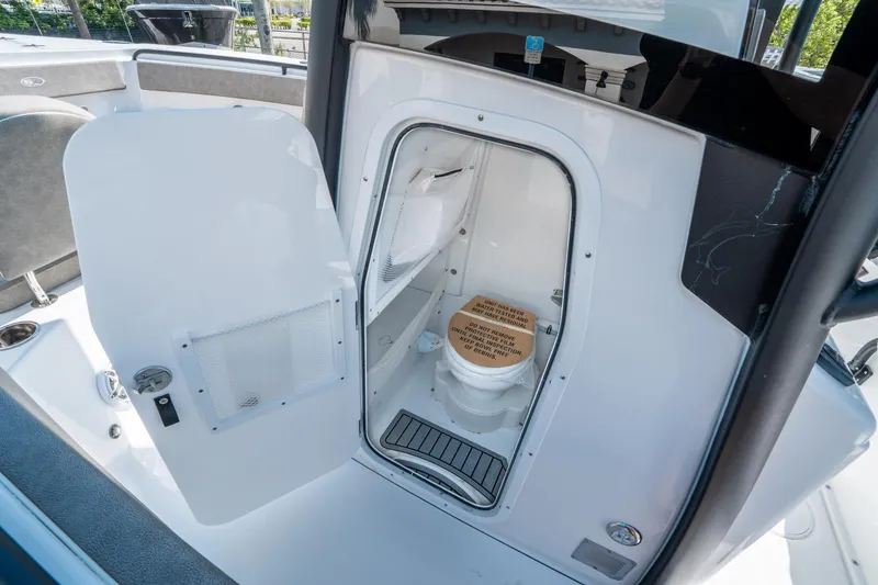 Slide: The Image of 2025 Sea Hunt Gamefish 25 boat interior with open door revealing compact marine toilet. - 24
