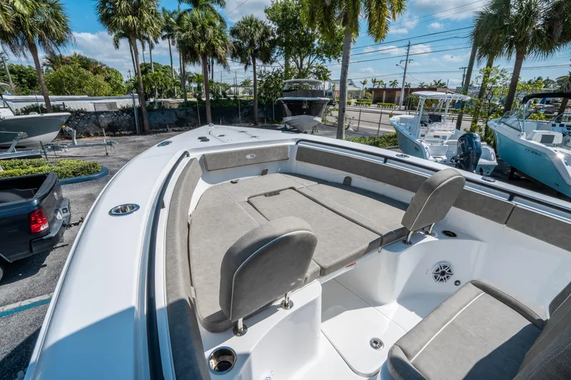 Slide: The Image of 2025 Sea Hunt Gamefish 25 boat interior with seating, surrounded by palm trees and parked boats. - 25
