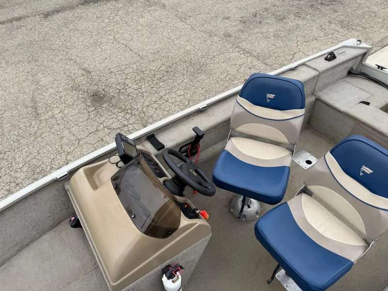 Slide: The Image of 1989 Fisher 16 Pro Avenger SC boat interior with blue and beige seats, steering console. - 11