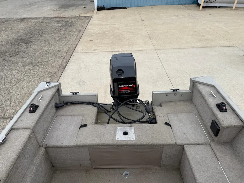 Slide: The Image of 1989 Fisher 16 Pro Avenger SC boat interior with motor, docked on concrete surface. - 17