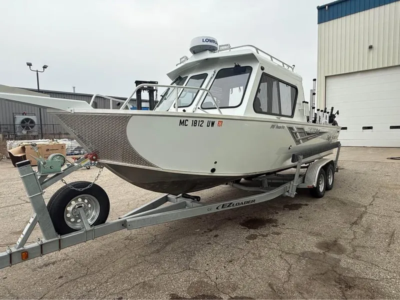 Slide: The Image of 2023 Hewescraft 240 Ocean Pro ET HT boat on trailer, parked outside a building. - 2