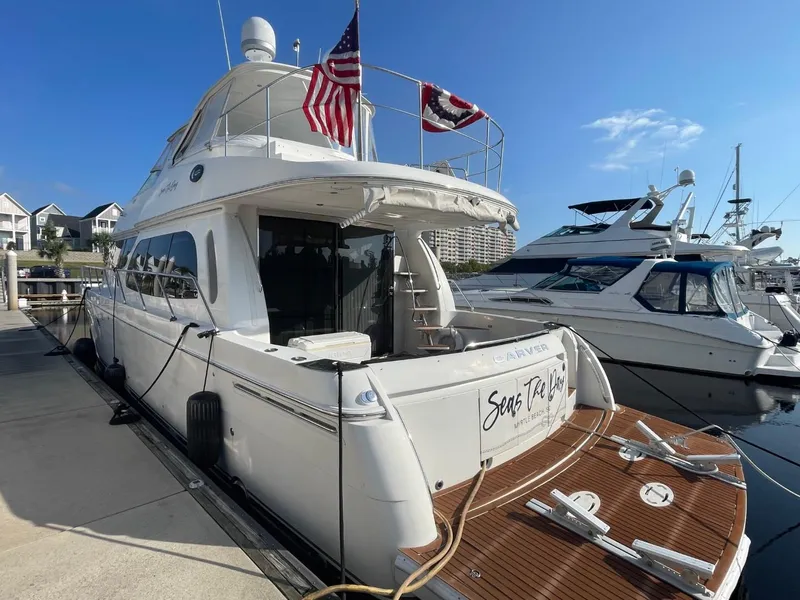 Slide: The Image of 2006 Carver 56 Voyager yacht docked, featuring flags and a spacious deck. - 11