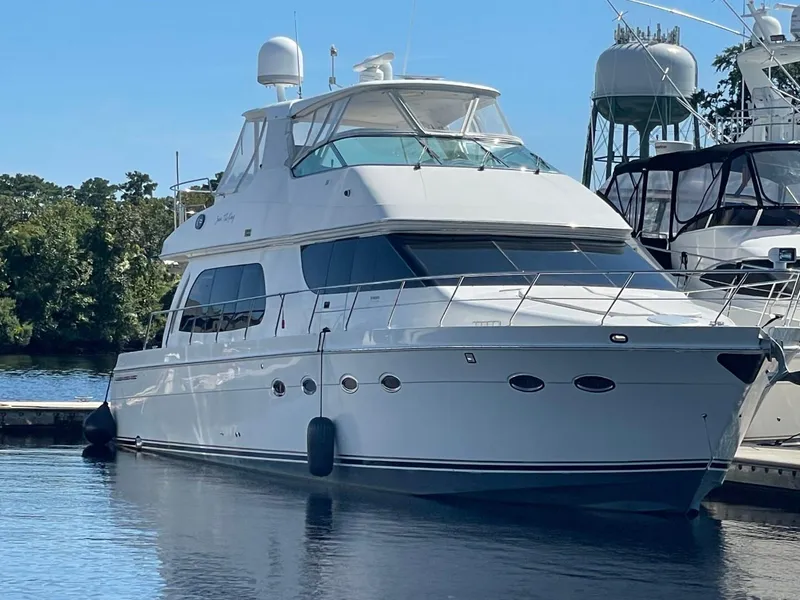 Slide: The Image of 2006 Carver 56 Voyager yacht docked in a marina, surrounded by trees and water. - 7