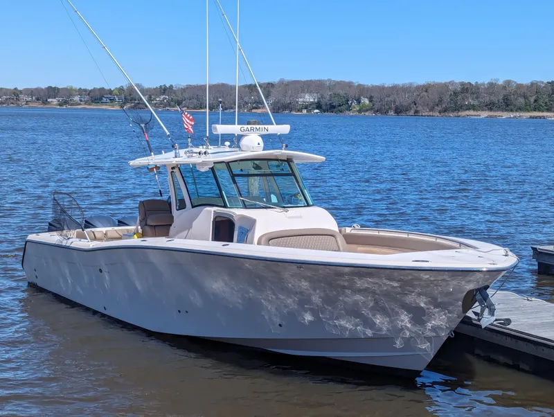 Slide: The Image of 2012 Grady-White Canyon 366 boat docked on a calm lake under clear blue skies. - 1