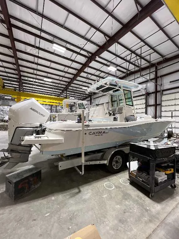 Slide: The Image of 2024 Caymas 281 HB boat in a warehouse, featuring a Mercury engine. - 1
