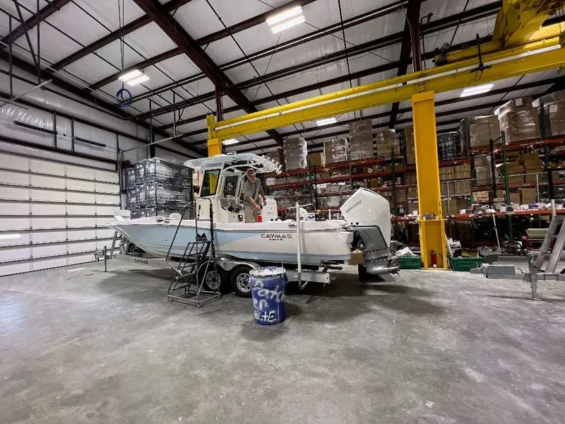 Slide: The Image of 2024 Caymas 281 HB boat in warehouse, on trailer, surrounded by industrial equipment. - 3