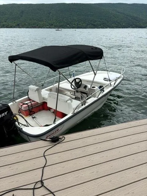 Slide: The Image of 2007 Boston Whaler 130 Sport boat docked on a lake with scenic mountain backdrop. - 2
