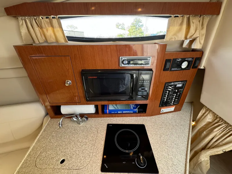 Slide: The Image of 2006 Regal 2565 Window Express boat interior with kitchenette, featuring microwave and stove. - 25