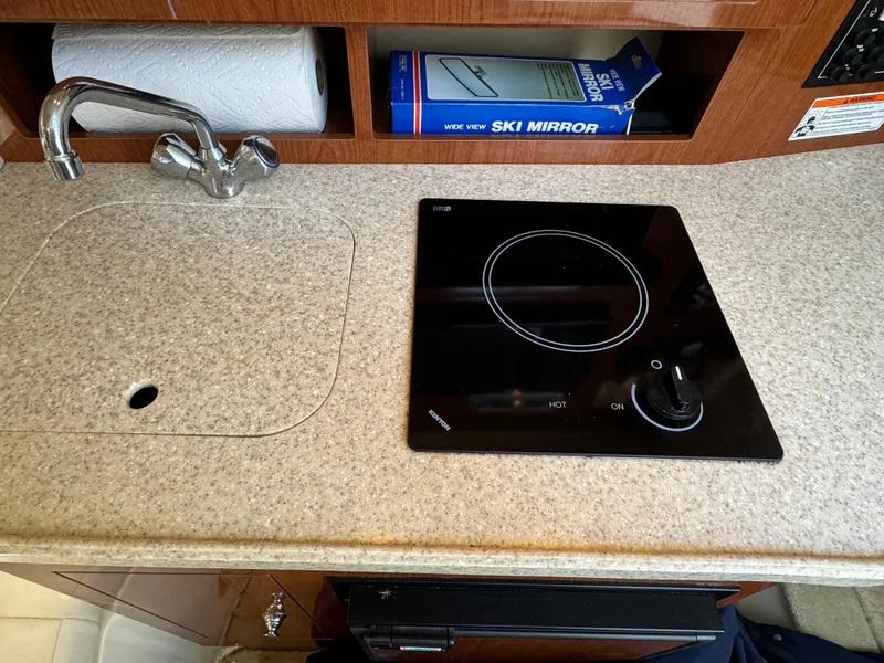 Slide: The Image of Compact kitchen area in a 2006 Regal 2565 Window Express boat with sink and stove. - 28