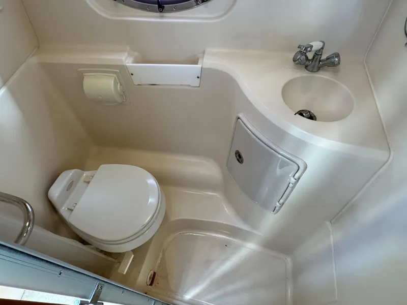 Slide: The Image of Compact bathroom in 2006 Regal 2565 Window Express boat, featuring toilet and sink. - 34