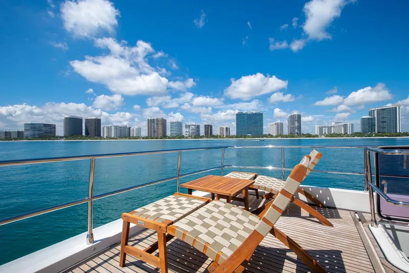 Slide: The Image of Luxury yacht deck with lounge chairs, table, and city skyline view under blue sky. Prestige 750, 2015. - 16