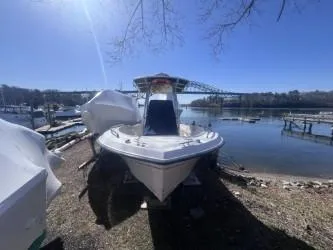 Slide: The Image of 2002 Grady-White Escape 209 boat docked by a serene lake under a clear blue sky. - 2