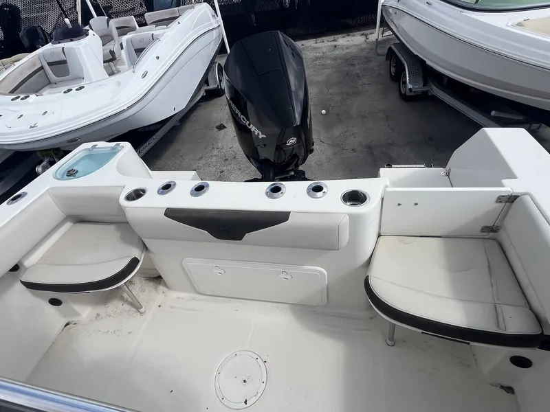 Slide: The Image of 2022 Sailfish 242 CC boat interior with seating and motor, docked alongside other boats. - 7