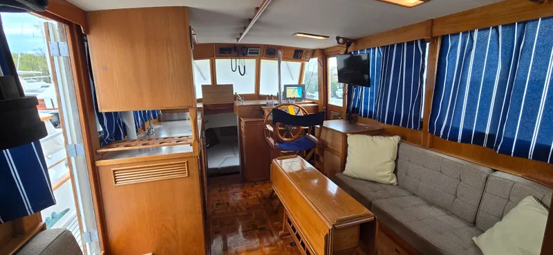 Slide: The Image of Interior of 1987 Grand Banks 36 Classic yacht with wood finish and blue-striped curtains. - 28