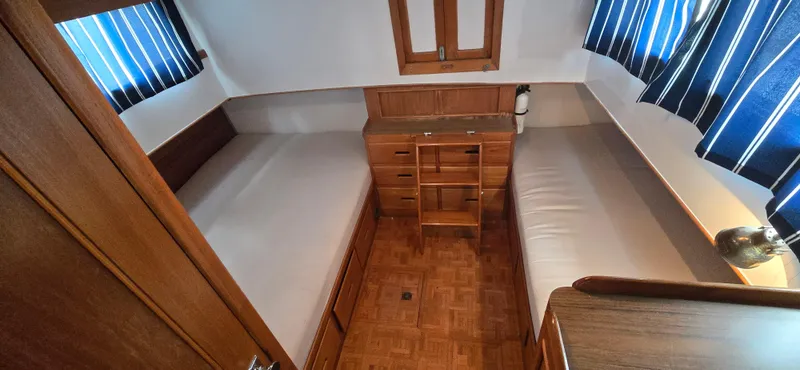 Slide: The Image of 1987 Grand Banks 36 Classic cabin with twin beds, wooden interior, and striped curtains. - 46