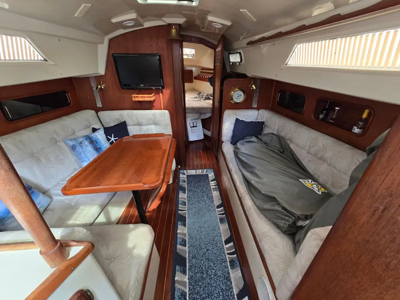 Slide: The Image of Interior of 1985 Mirage Yachts 35, featuring cozy seating, wooden table, and nautical decor. - 3