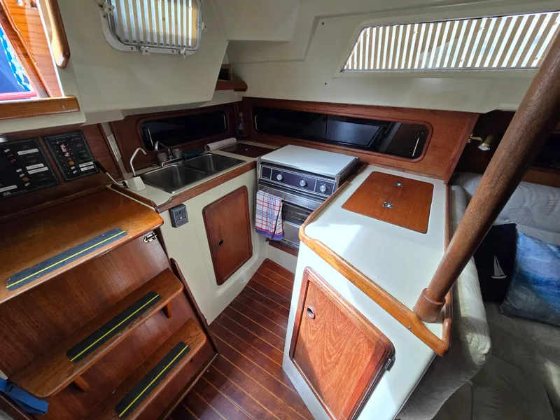 Slide: The Image of 1985 Mirage Yachts 35 interior with wooden cabinetry, compact kitchen, and cozy seating area. - 5