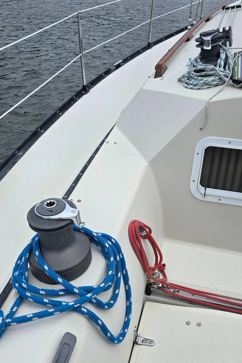 Slide: The Image of 1985 Mirage Yachts 35 sailboat deck with winch and ropes, on calm water. - 8