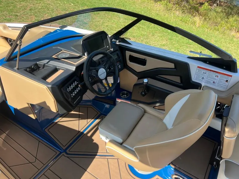 Slide: The Image of 2021 Moomba Makai boat interior with tan seats, modern dashboard, and steering wheel. - 13