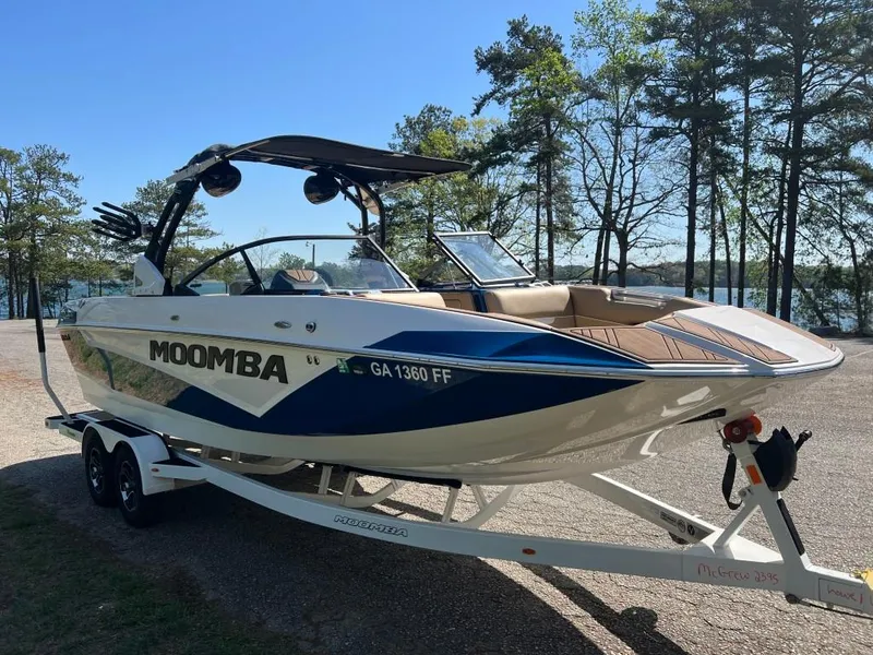 Slide: The Image of 2021 Moomba Makai boat on trailer, parked near a lake with trees in the background. - 7