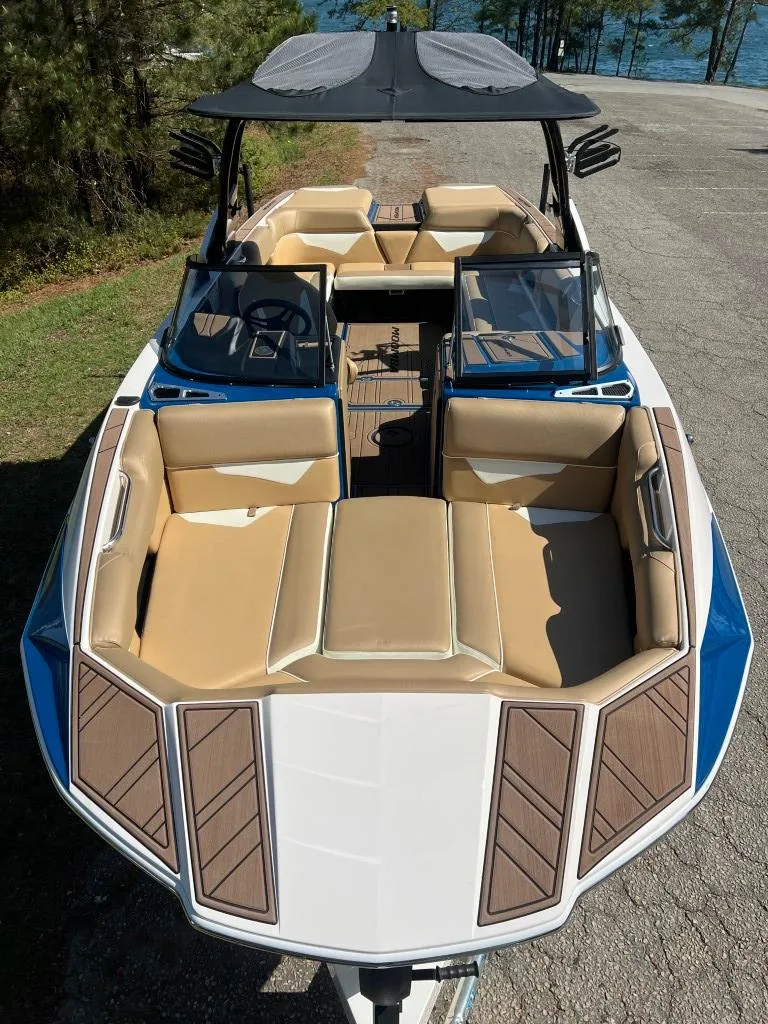 Slide: The Image of 2021 Moomba Makai boat with tan seating and sleek design, parked near a lake. - 8