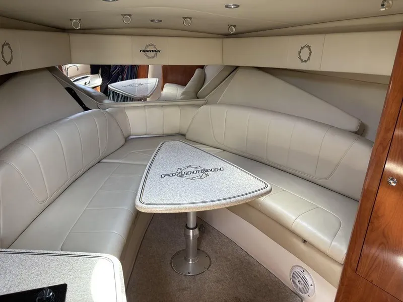 Slide: The Image of 2008 Fountain 33 Sportfish Cruiser interior with beige seating and triangular table. - 15